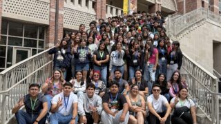 Group of students pose together on campus steps at USC.